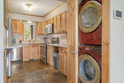 a kitchen with wooden cabinets and a washer and dryer at Buffalo Woods 216 - Wildernest in Silverthorne