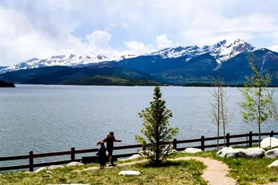 two people standing next to a fence near a lake at Lake Ridge at Lake Dillon in Dillon