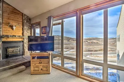 a living room with a tv and a large window at Ski-InandSki-Out Granby Ranch Home Mountain Views! in Granby