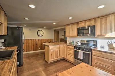 a kitchen with wooden cabinets and a black refrigerator at Wildmanor Ranch Near Red Rocks with Hot Tub! in Morrison