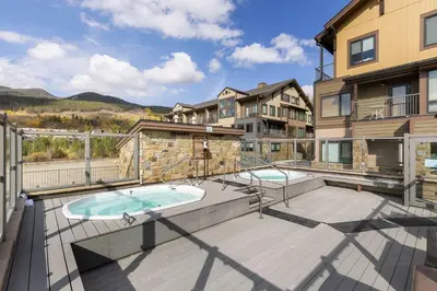 an apartment patio with a hot tub and a building at 2754 Slopeside condo in Keystone