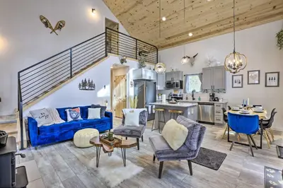 a living room with a blue couch and chairs and a kitchen at 1 Mi to St Marys Glacier Trail Modern Mtn Cabin! in Idaho Springs