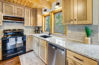 a kitchen with wooden cabinets and a stove and a sink at Dreamy Escape Btwn Winter Park and Lake Granby! in Tabernash