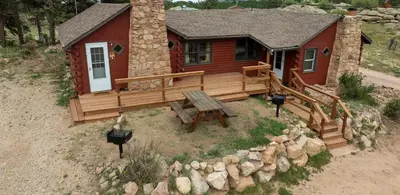 a log cabin with a wooden deck and a picnic table at Marr's Mountain Cabins in Red Feather Lakes