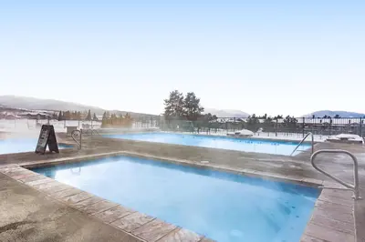 a swimming pool with blue water and mountains in the background at Railbender 8 in Fraser