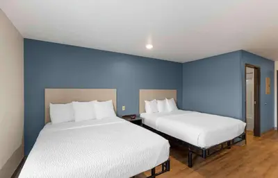 two beds in a room with blue walls at Extended Stay America Select Suites - Firestone in Firestone