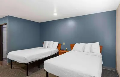 two beds in a room with a blue wall at Extended Stay America Select Suites - Loveland in Loveland