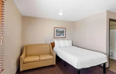 a bed and a chair in a room at Extended Stay America Select Suites - Loveland in Loveland
