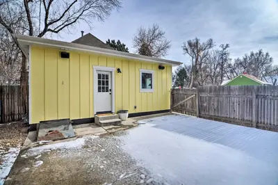 a small yellow house with a wooden fence at Contemporary Longmont Hideaway in Old Town! in Longmont