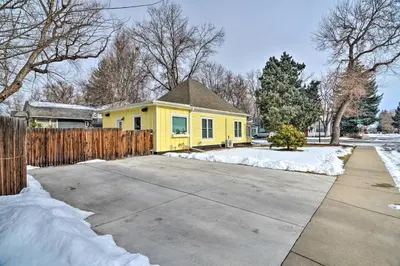 a yellow house with a fence in the snow at Contemporary Longmont Hideaway in Old Town! in Longmont