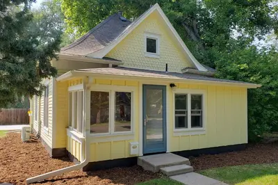 a small yellow house with a blue door at Contemporary Longmont Hideaway in Old Town! in Longmont