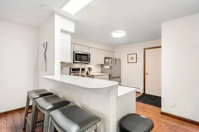a white kitchen with a counter and stools in it at Meadow Lodge - Dog Friendly! in Frisco