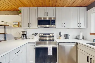 a kitchen with white cabinets and stainless steel appliances at Fraser Family Getaway in Fraser