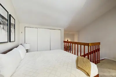 a bedroom with a white bed and a staircase at Fraser Family Getaway in Fraser