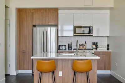 a kitchen with an island with two orange bar stools at A Denver Skyline State of Mind - Zuni Lofts in Denver