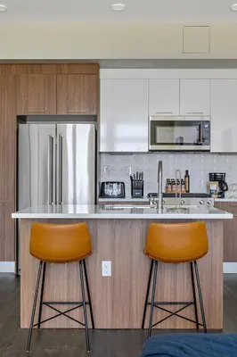 a kitchen with two bar stools and a refrigerator at A Denver Skyline State of Mind - Zuni Lofts in Denver