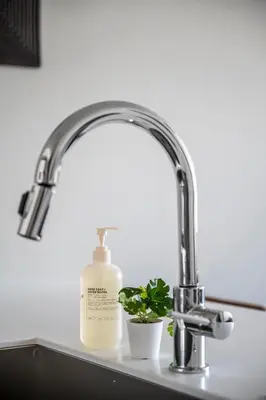 a sink with a bottle of soap and a plant at Top Floor - Amazing Windows - Zuni Lofts in Denver