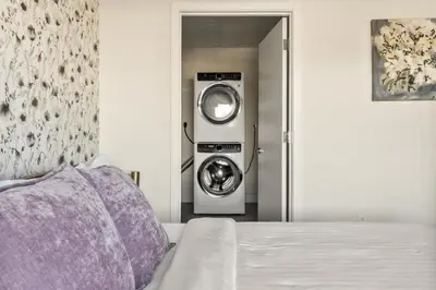a washer and dryer in a room with a bed at Top Floor - Amazing Windows - Zuni Lofts in Denver