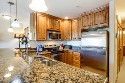 a kitchen with wooden cabinets and a stainless steel refrigerator at Central Fraser Condo 8 Mi to Winter Park Ski! in Fraser