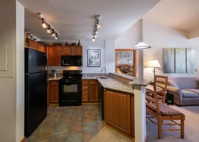 a kitchen with a black refrigerator and a table at Zephyr Mountain Lodge Select-Rated 1602 in Winter Park