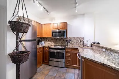 a kitchen with wooden cabinets and a stainless steel refrigerator at Perfectly Cozy 3rd floor Zephyr Mountain Lodge Condo with remodeled bath condo in Winter Park