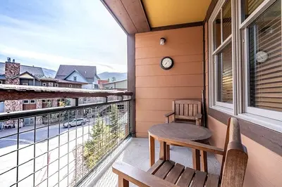 a balcony with a table and a clock on a window at Perfectly Cozy 3rd floor Zephyr Mountain Lodge Condo with remodeled bath condo in Winter Park