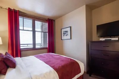 a bedroom with a bed and a tv and a window at Ski-In Ski-Out Cozy 4th Floor Zephyr Mountain Lodge Condo Tucked Into The Woods condo in Winter Park