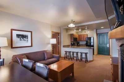 a living room and kitchen with a couch and a table at Ski-In Ski-Out Cozy 4th Floor Zephyr Mountain Lodge Condo Tucked Into The Woods condo in Winter Park
