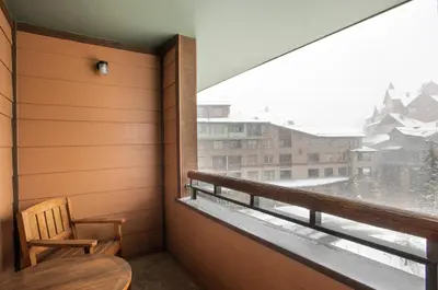 a balcony with a wooden chair and a window at Ski-In Ski-Out Cozy 4th Floor Zephyr Mountain Lodge Condo Tucked Into The Woods condo in Winter Park