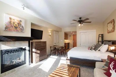 a bedroom with a king sized bed and a fireplace at Beautiful Ski-In Ski-Out Top Floor Studio Condo at Fraser Crossing Founders Pointe condo in Winter Park