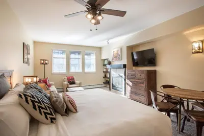 a bedroom with a large bed and a living room at Beautiful Ski-In Ski-Out Top Floor Studio Condo at Fraser Crossing Founders Pointe condo in Winter Park