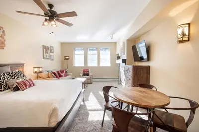 a living room with a bed and a table at Beautiful Ski-In Ski-Out Top Floor Studio Condo at Fraser Crossing Founders Pointe condo in Winter Park