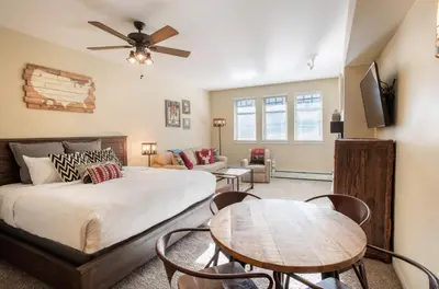 a bedroom with a bed and a table with chairs at Beautiful Ski-In Ski-Out Top Floor Studio Condo at Fraser Crossing Founders Pointe condo in Winter Park