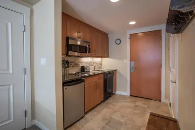 a kitchen with wooden cabinets and a sink and a microwave at Beautiful Ski-In Ski-Out Top Floor Studio Condo at Fraser Crossing Founders Pointe condo in Winter Park