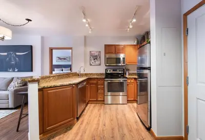 a kitchen with wooden cabinets and stainless steel appliances at Wonderful Zephyr Mountain Lodge condo with forest views - close to gondola condo in Winter Park