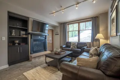 a living room with a leather couch and a fireplace at Ski Slope View Remodeled Zephyr Mountain Lodge Condo condo in Winter Park