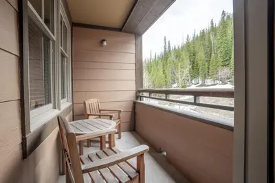 two chairs and a table on a porch with a window at Ski Slope View Remodeled Zephyr Mountain Lodge Condo condo in Winter Park