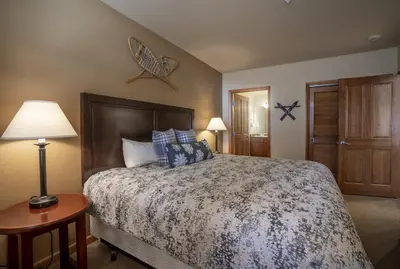 a bedroom with a bed and a table with a lamp at Ski Slope View Remodeled Zephyr Mountain Lodge Condo condo in Winter Park