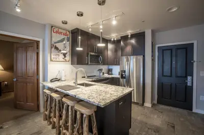 a kitchen with a counter with a sink and a refrigerator at Ski Slope View Remodeled Zephyr Mountain Lodge Condo condo in Winter Park