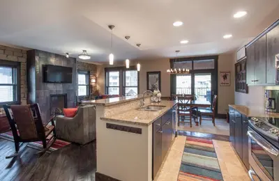a kitchen and living room with a sink and a counter at Spacious Village View Townhouse with Fireplace at Parry Peak Lofts townhouse in Winter Park
