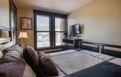 a bedroom with a bed and a flat screen tv at Spacious Village View Townhouse with Fireplace at Parry Peak Lofts townhouse in Winter Park