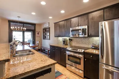a kitchen with wooden cabinets and stainless steel appliances at Spacious Village View Townhouse with Fireplace at Parry Peak Lofts townhouse in Winter Park