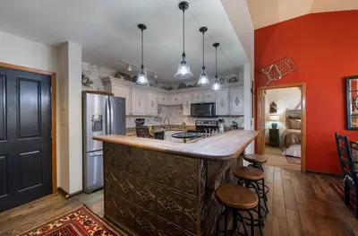 a kitchen with a large wooden bar with stools at Top Floor Condo with Views of Ski Slopes and Gondola in Zephyr Mountain Lodge condo in Winter Park