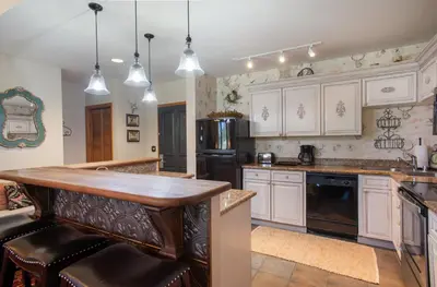 a kitchen with white cabinets and a wooden counter top at Top Floor Condo with Views of Ski Slopes and Gondola in Zephyr Mountain Lodge condo in Winter Park