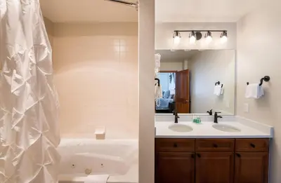 a bathroom with a tub and a sink and a mirror at Zephyr Mountain Lodge Premium-Rated 1705 in Winter Park
