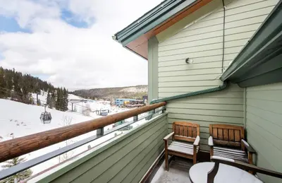 two chairs on a balcony with a view of the snow at Zephyr Mountain Lodge Premium-Rated 1705 in Winter Park