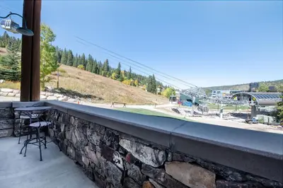 a balcony with a stone wall and a table and chair at Zephyr Mountain Lodge - Premium Rated Condo 1217 in Winter Park