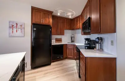 a kitchen with a black refrigerator and wooden cabinets at Zephyr Mountain Lodge - Premium Rated Condo 1217 in Winter Park