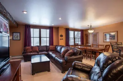 a living room with a leather couch and a table at Premium Ski-Slope View Two Bedroom Zephyr Mountain Lodge Condo condo in Winter Park