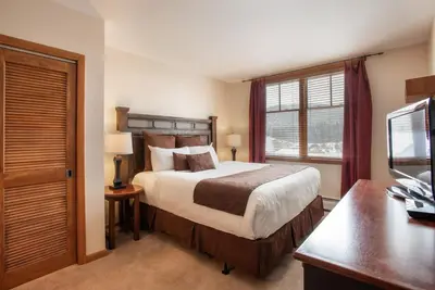 a bedroom with a bed and a desk and a television at Roomy Zephyr Mountain Lodge Condo with Perfect Slope View from Balcony condo in Winter Park